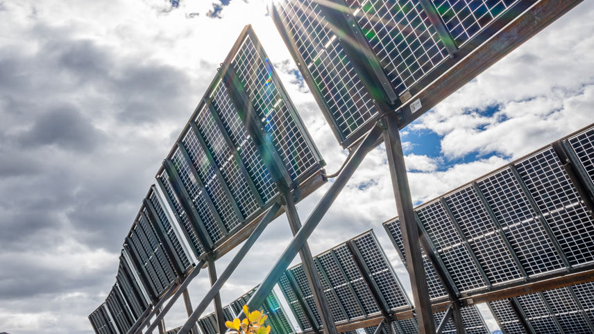 Solaranlage Madrisa Solar: Photovoltaikmodule in alpiner Landschaft, Sonne scheint durch Wolken.