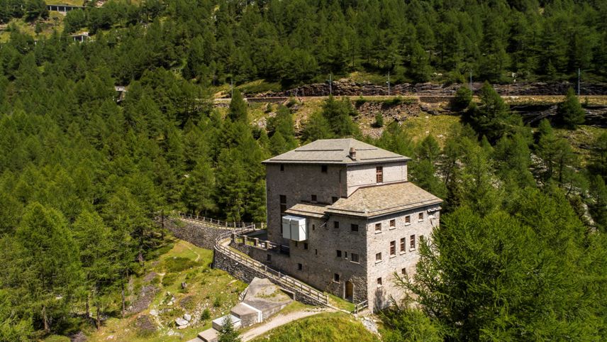 Das historische Kraftwerksgebäude Palü, eingebettet in einen dichten Bergwald inmitten der Bündner Alpen.