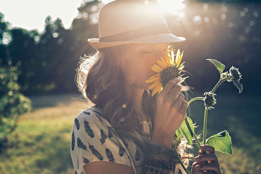 Frau riecht an Sonneblume als Zeichen einer erneuerbaren Energiewirtschaft