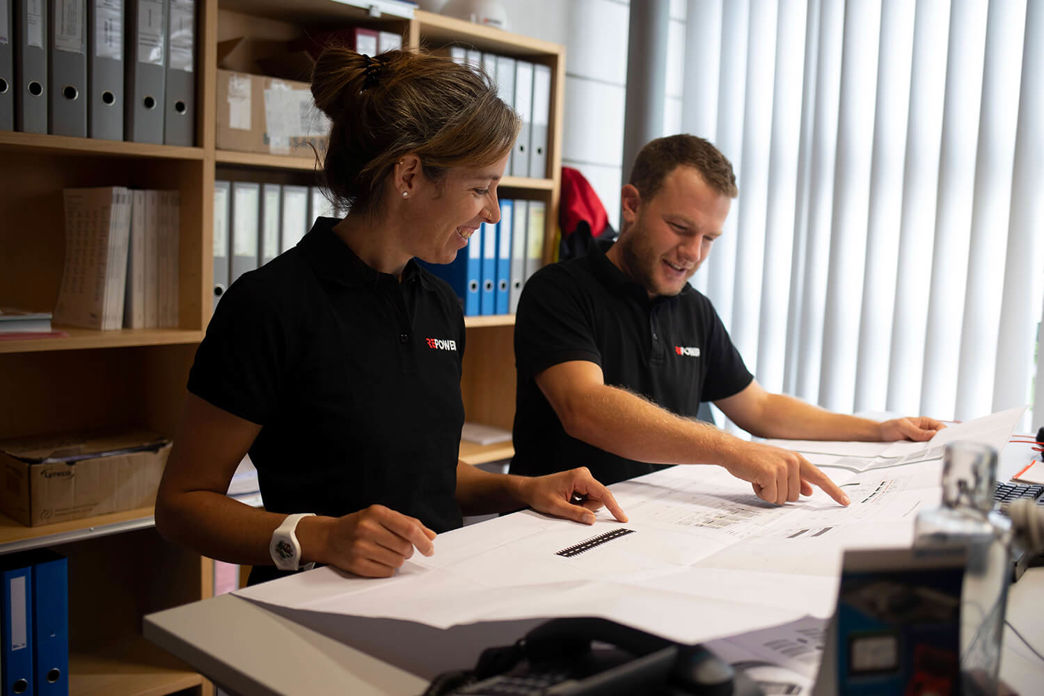 Due progettisti elettrici controllano i piani di un edificio.