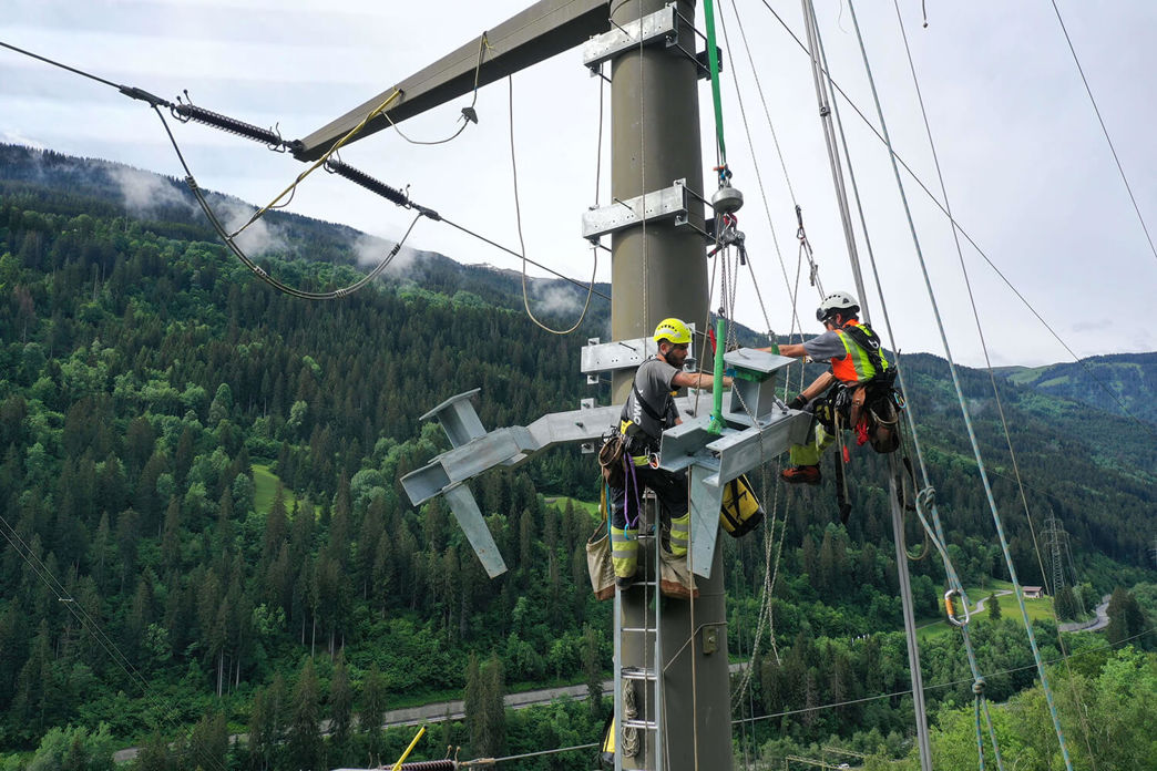 Elettricista di rete durante interventi di riparazione su un traliccio elettrico.