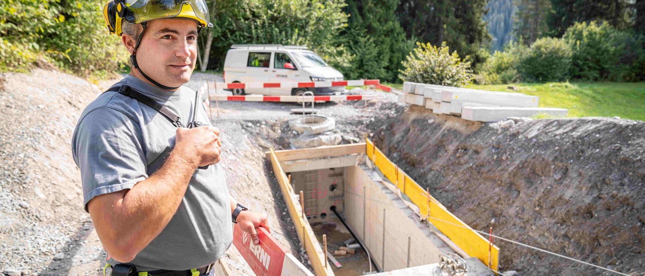 Ein Repower-Mitarbeiter mit Helm bei einem offenen Kabelschacht in Laax – der letzte Strommast wird entfernt.